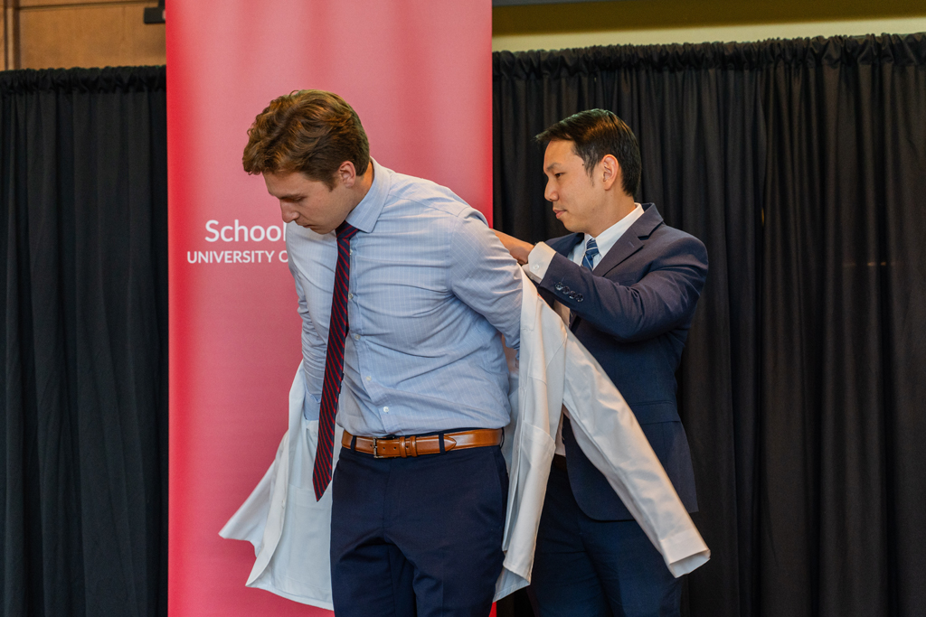 A student receives his white coat from Sean Lim