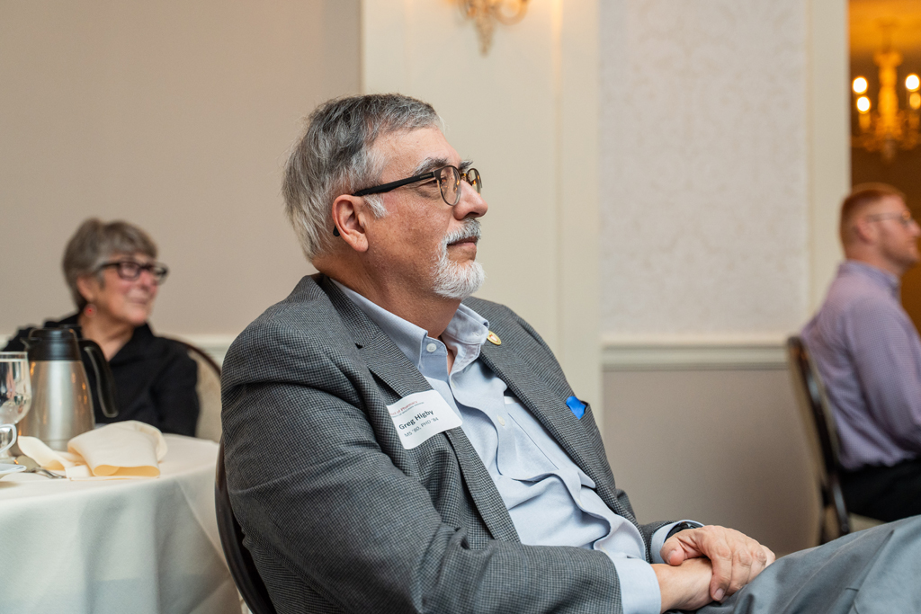 Greg Higby sits at a table and listens