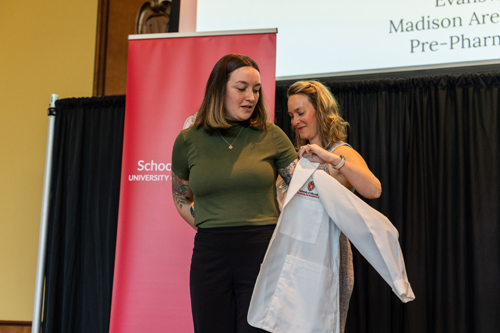 A student receives her white coat from Kate Rotzenberg