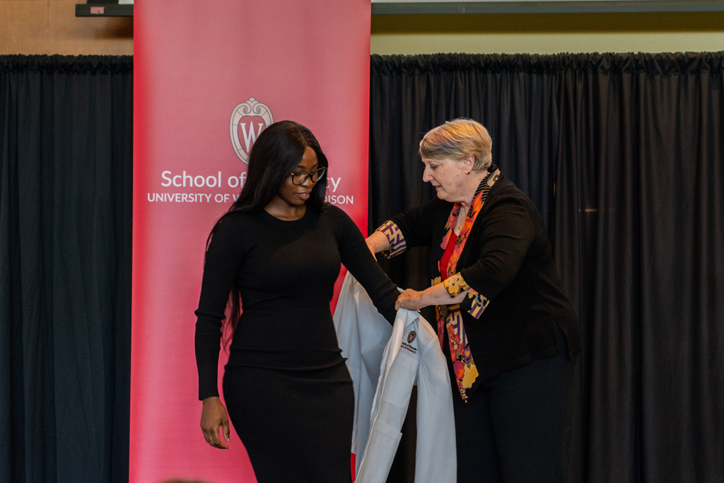 A student receives her white coat from Karen Kopacek