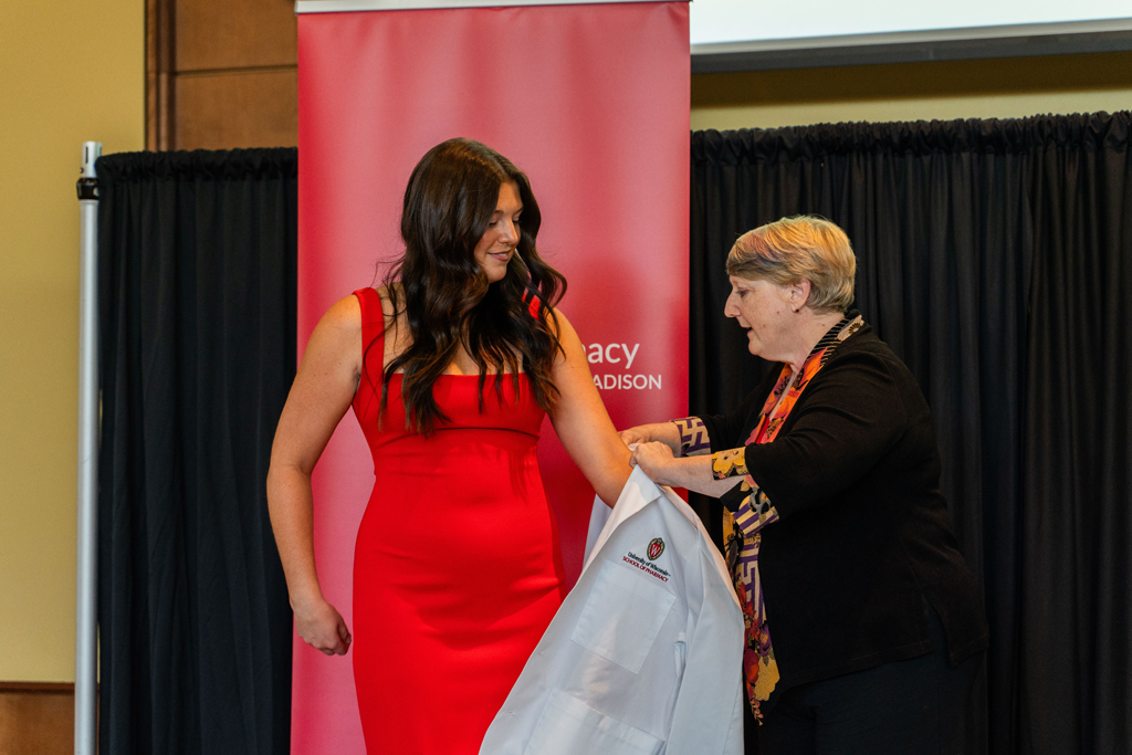 A student receives her white coat from Karen Kopacek