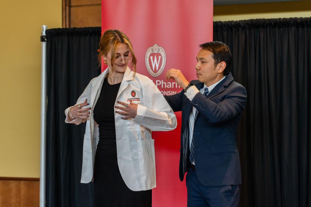 A student receives her white coat from Sean Lim