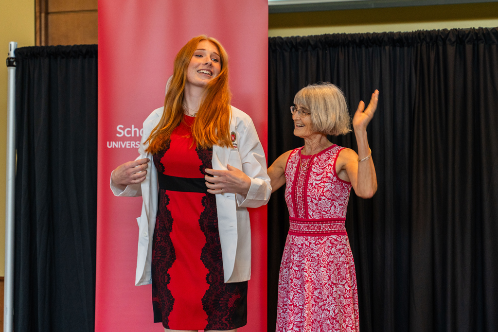 A student receives her white coat from Mara Kieser