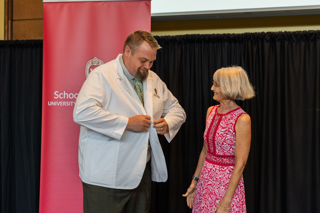 Mara Kieser watches as a student buttons his white coat