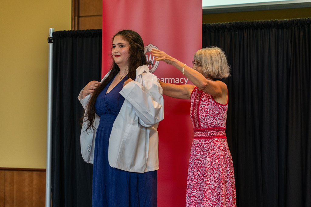 Mara Kieser places a white coat on a student