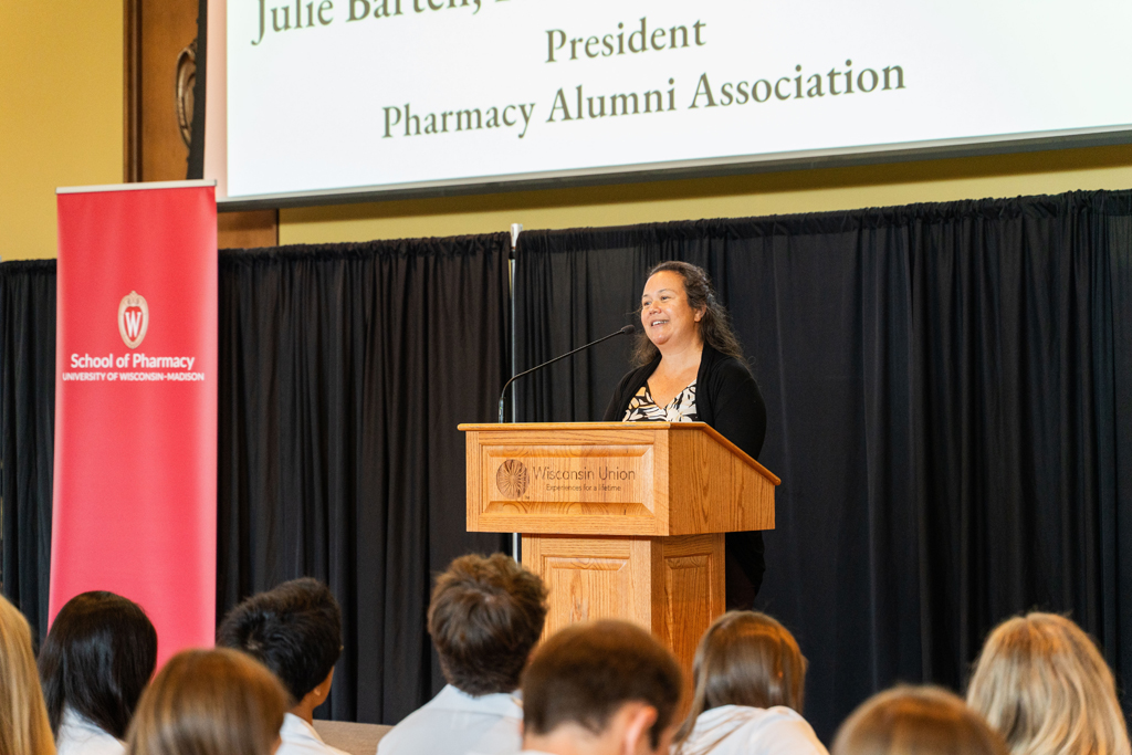 Julie Bartell speaks at a podium in front of the seated Class of 2028