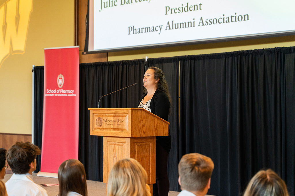 Julie Bartell speaks at a podium in front of the seated Class of 2028