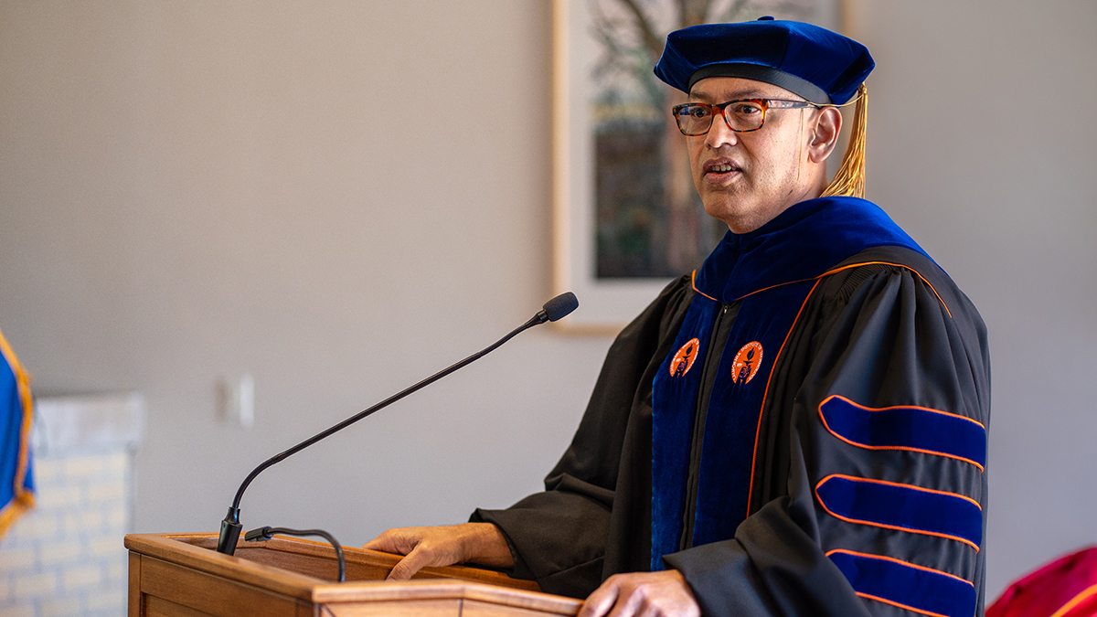 Arash Bashirullah in graduation regalia at a podium