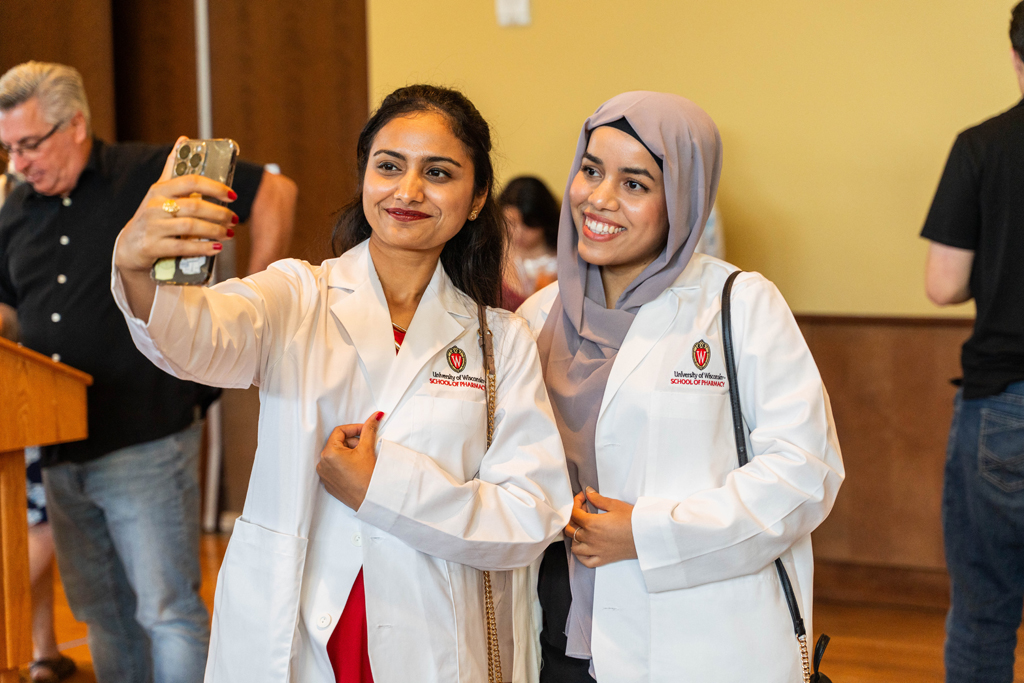 Two female students in white coats take a smiling selfie