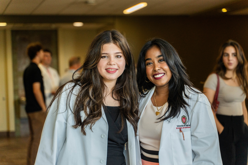 Two students in white coats pose for a photo