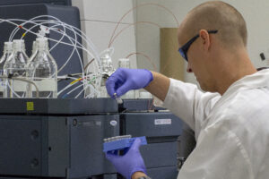 A researcher in a white coat pipetting in a lab.