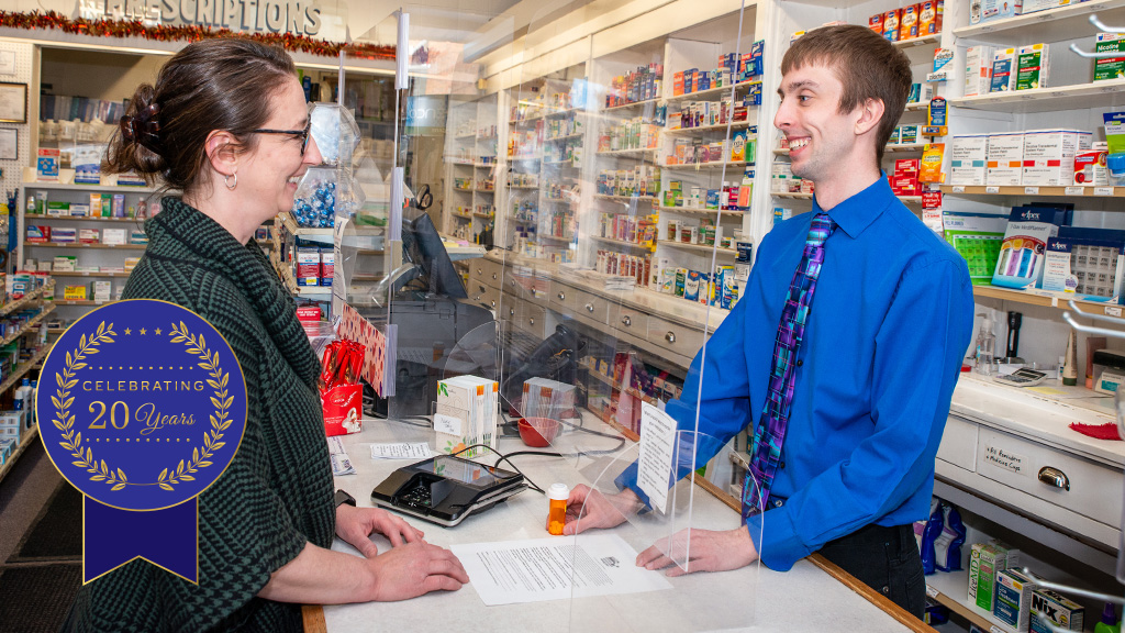 banner image: a community pharmacist counsels a patient at the register.
