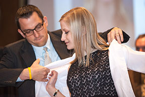 Pharmacy Alumni Association President John Konkol presents a DPH-1 student with her white lab coat. Photo taken by Todd Brown, Media Solutions, School of Medicine and Public Health.