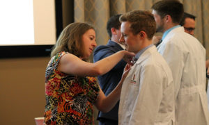 Marking the completion of the third year of pharmacy school, Henry Bertram (right), receives his pin from alumna Kim Lintner, PharmD, at the DPH-3 Pinning Ceremony held May 4, 2017.
