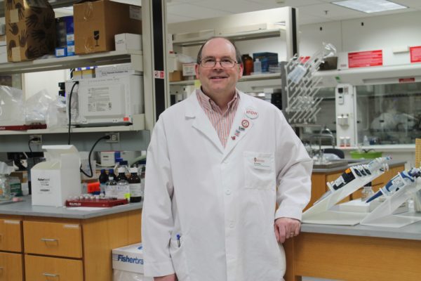 Ed Elder wearing a white coat in a lab
