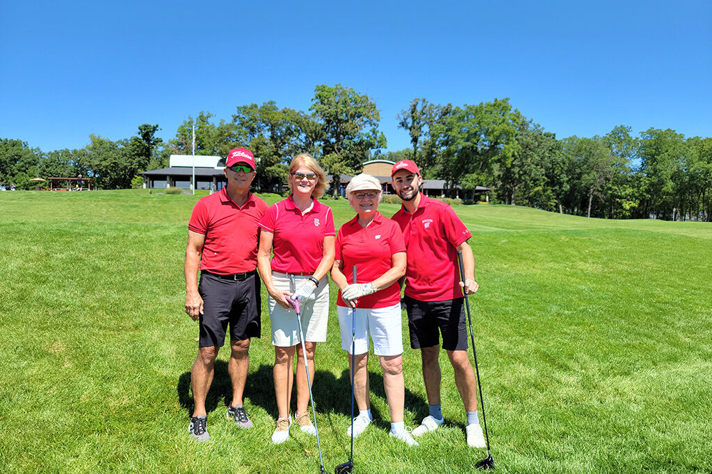 Pharm alumni wearing red together with golf clubs