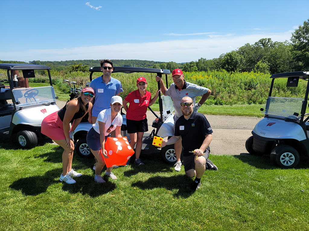 UW Pharmacy Alumni together next to golf cart