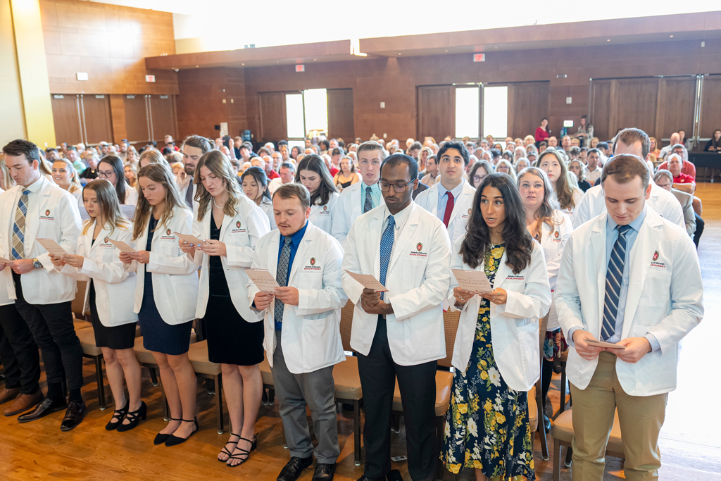 Students in white coats reading off flyer