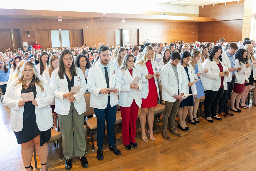Students in white coats reading their flyers