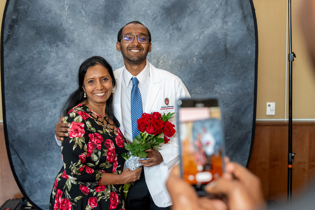 Student smiling and posing together with his mother who has roses in her hand