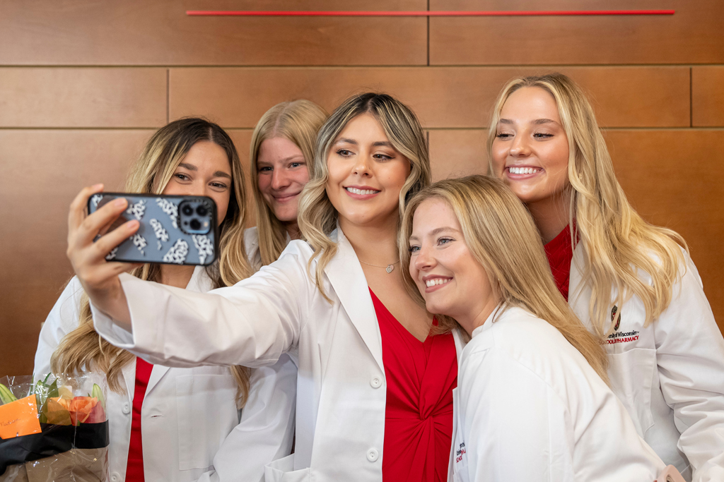 Students in white coats grouped together for a selfie