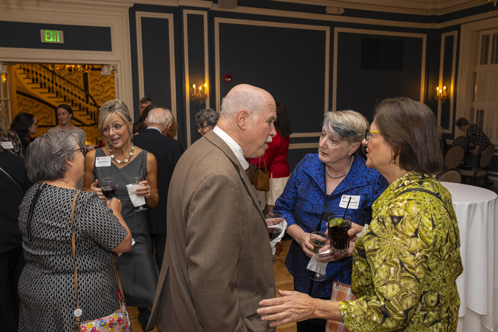 Beth Martin speaks with an attendee in the background, while James DeMuth and Karen Kopacek speak with another attendee in the foreground