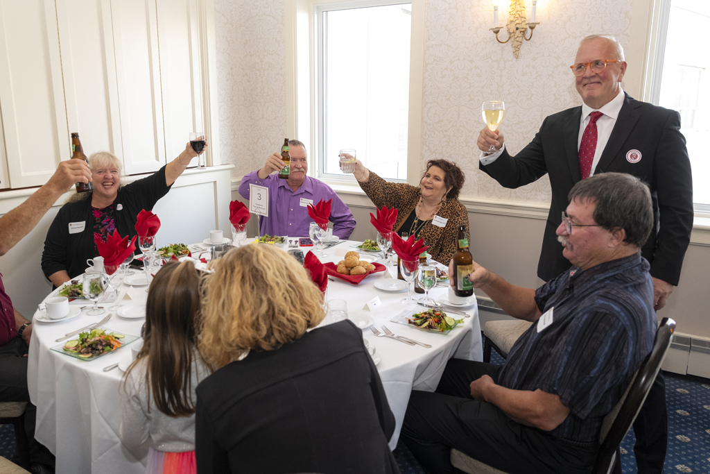 Tom McCourt holds his drink up in a toast with those at his table