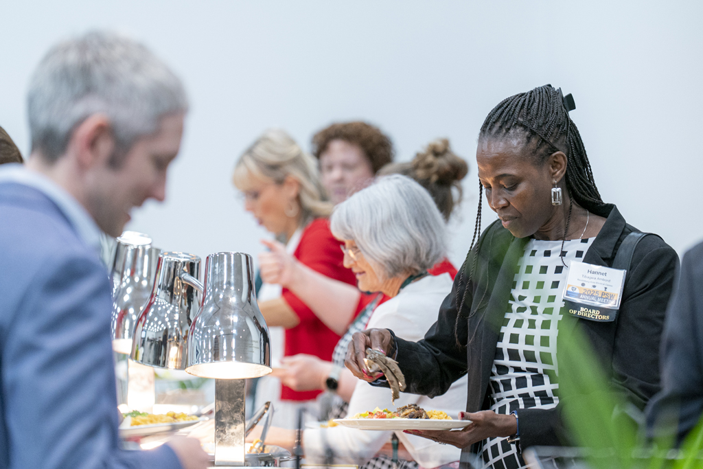 Attendees holding plates go through the buffet line