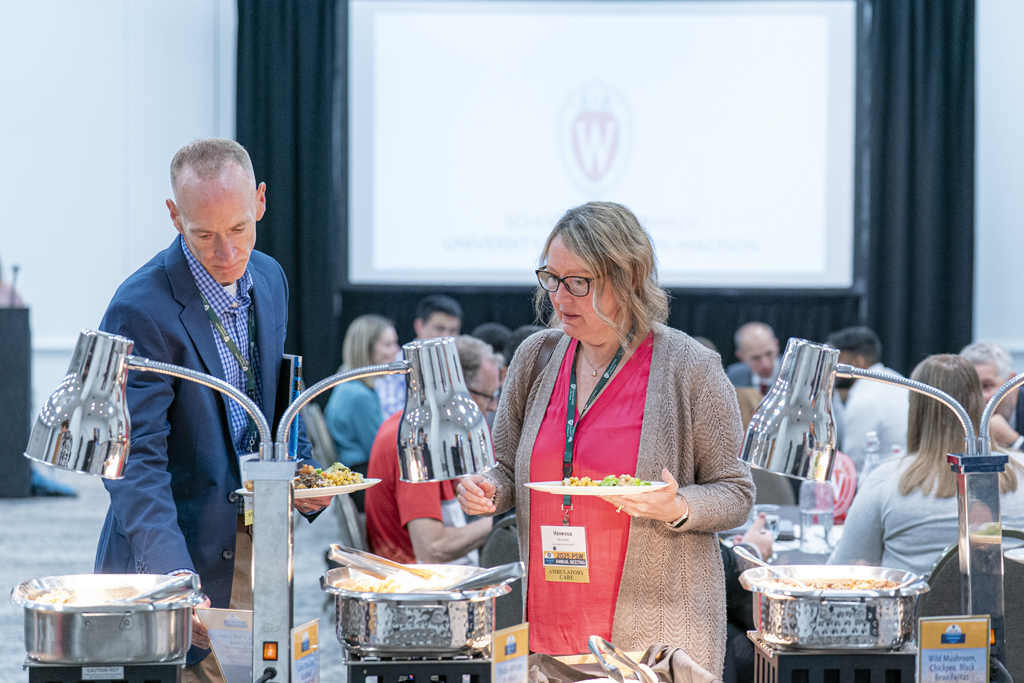 Attendees holding plates go through the buffet line