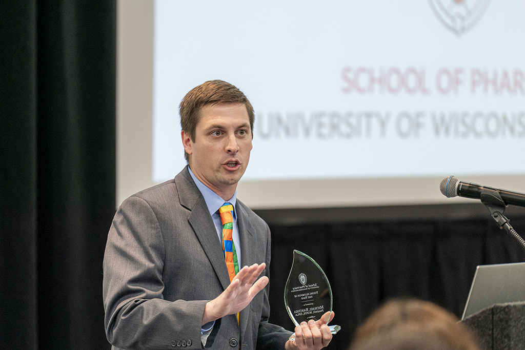 Mike Raschka speaks at a podium while holding his award