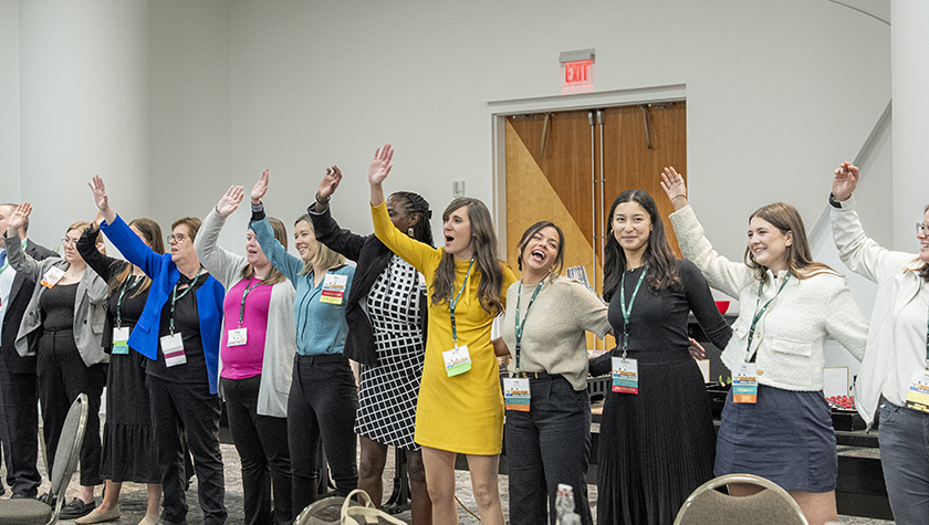 Alumni standing together with arms waving in the air