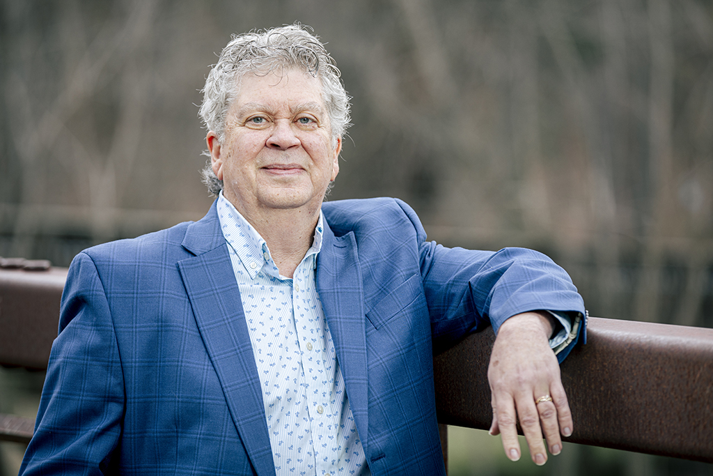 Elliott Sogol portrait of him leaning on a bridge