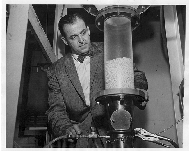 Dale Wurster next to his air-suspension chamber that applies coatings to tablets.