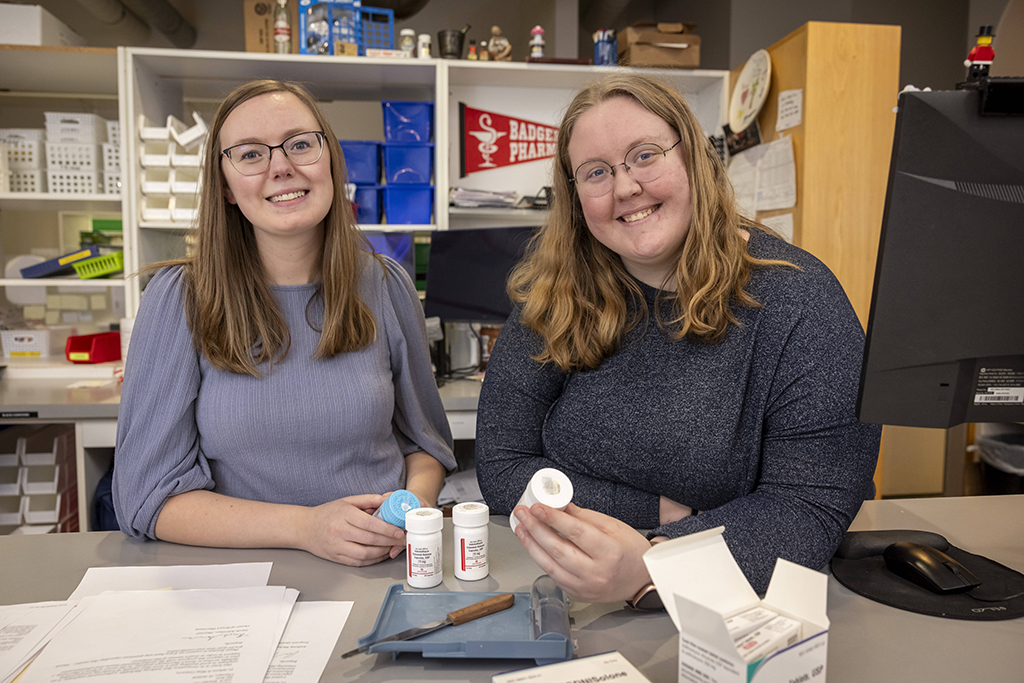Rachel Whitesitt and Kelly Goyle smile for a photo in a pharmacy