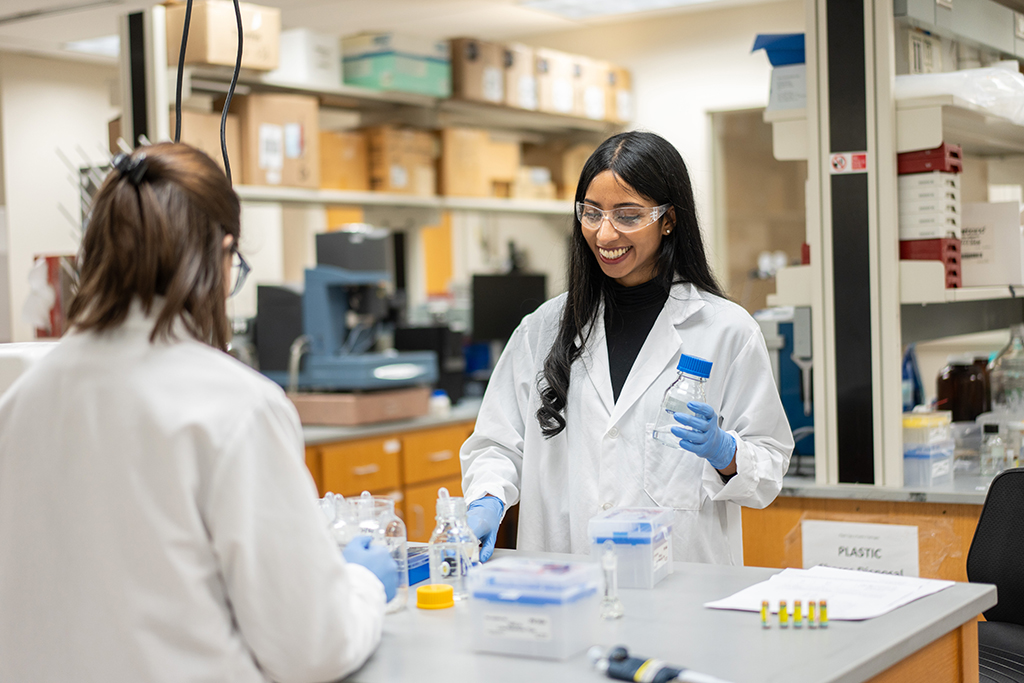 Apoorva Reddy wearing a white coat in goggles, working in a lab