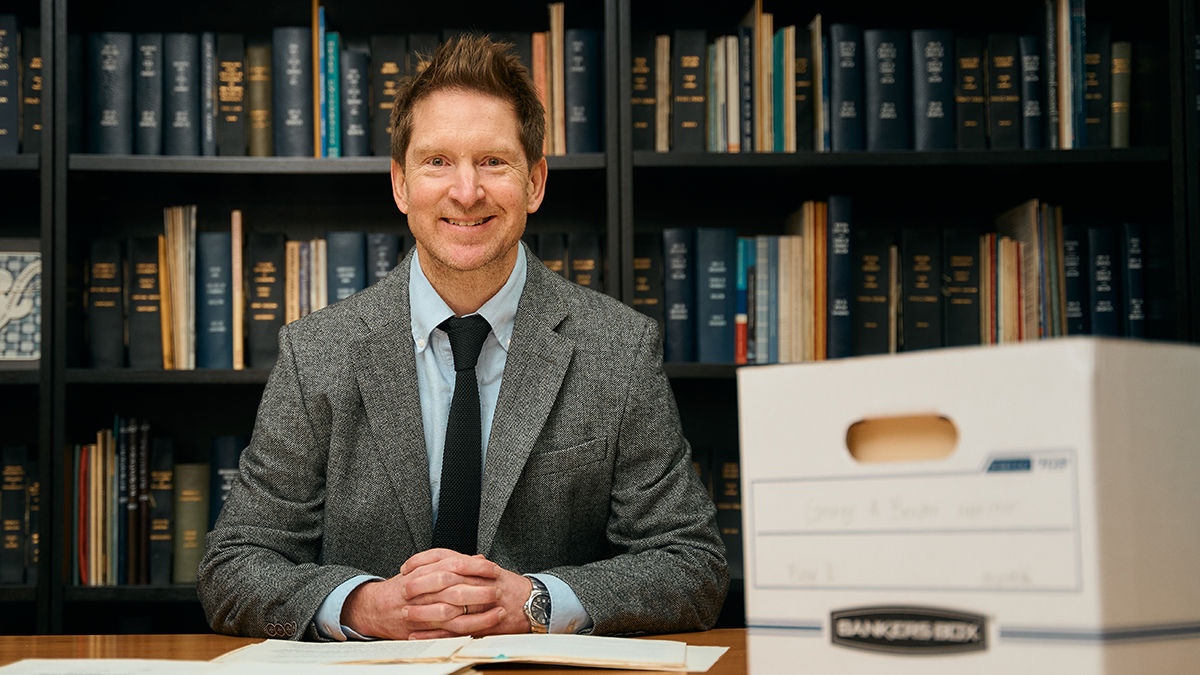 Professor Lucas Richert portrait next to a cardboard archive box