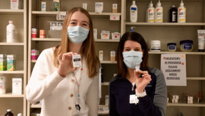 Anna Lattos and Kate Cain holding vials of COVID vaccine