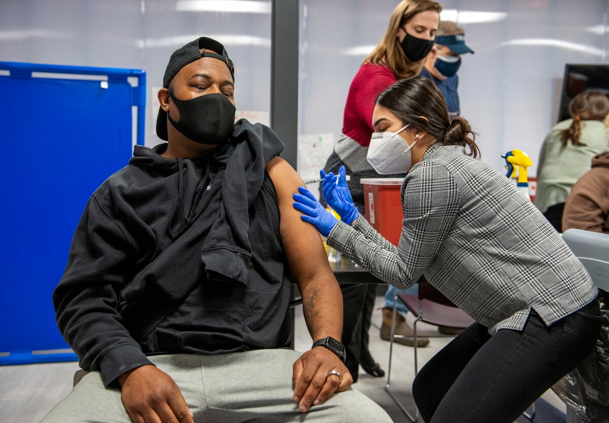 PharmD student Mahnoor Khan administers a vaccine to a patient in a black shirt. 