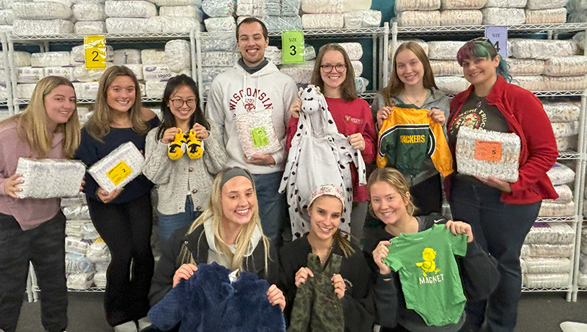 PharmD students pose with baby clothes, diapers, and other supplies while volunteering at Babies and Beyond.