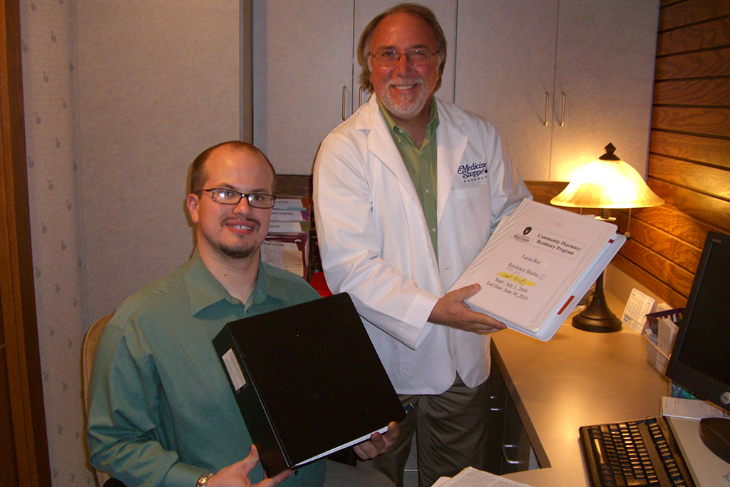 Lucas Boe and Brian Jensen hold up binders in an office