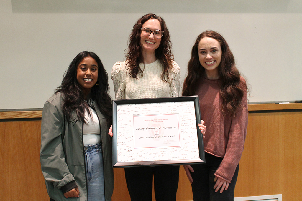 Casey Gallimore receiving her Teacher of the Year award from two PharmD students