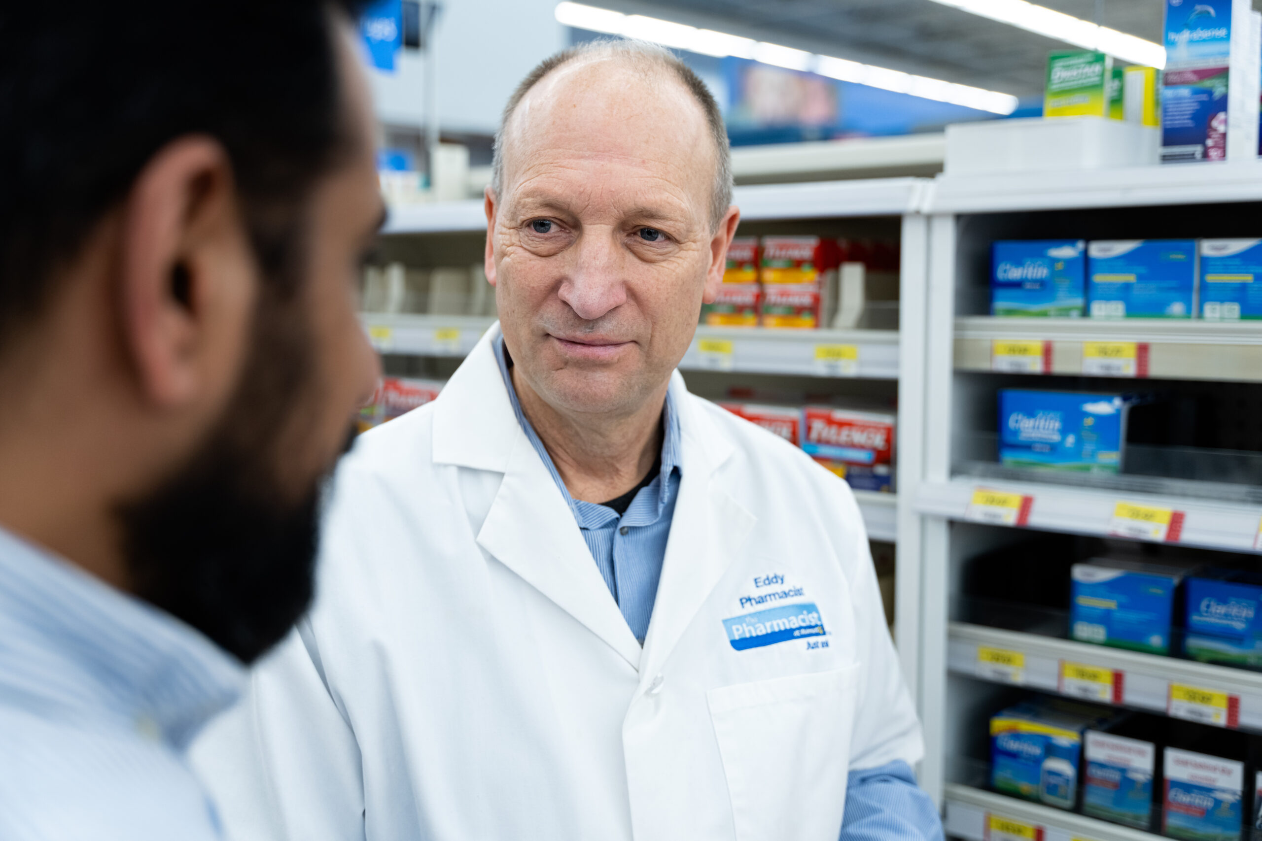 Ed Lebler speaks with a patient at his pharmacy.