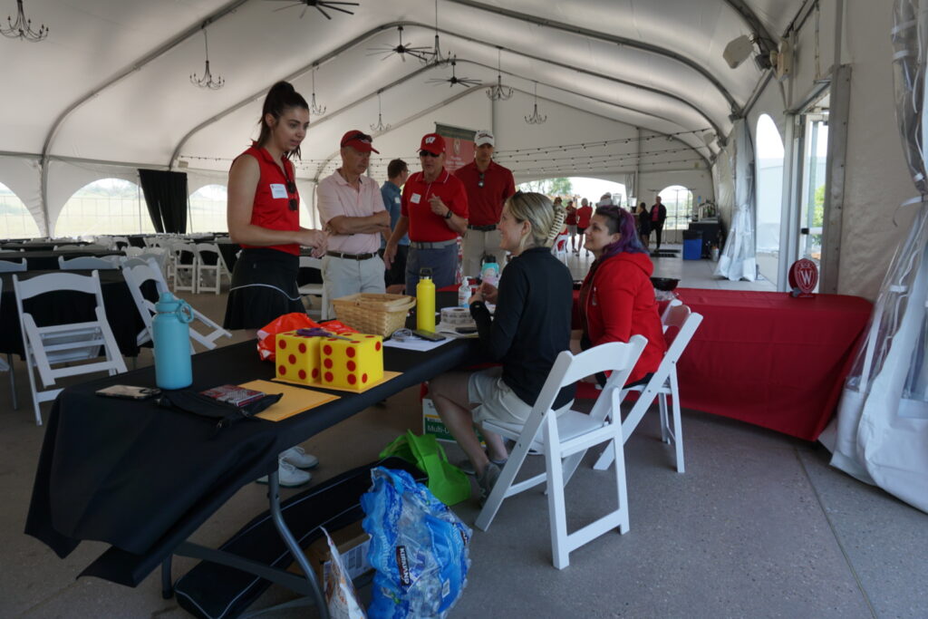 Event coordinators at a table with props and tickets under a large pavillion.
