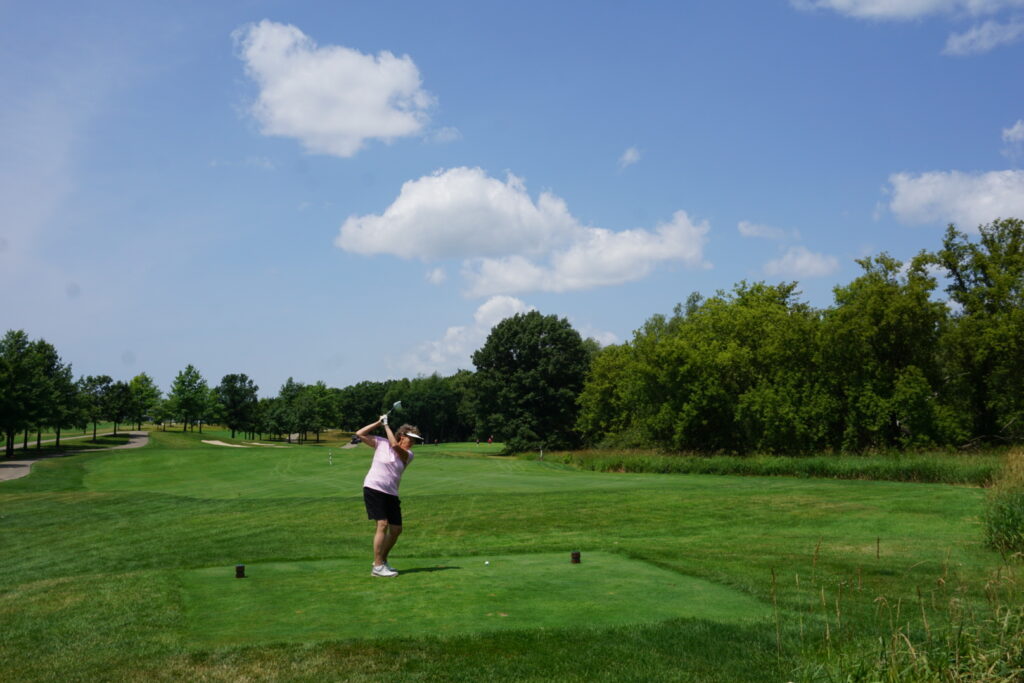 A badger alumni mid-swing at a golf course
