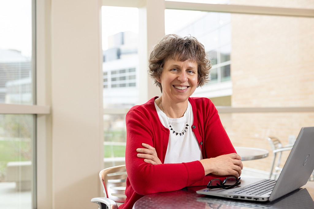 Denise Walbrandt Pigarelli poses by her laptop in the School's atrium