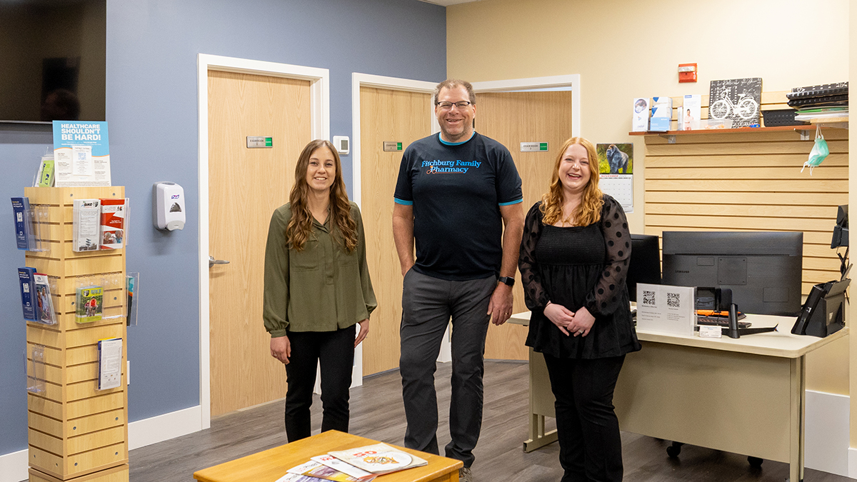 Emma Hickmann, Thad Schumacher, and Bianca Bellissimo stand and smile in the lobby of Fitchburg Family Clinic