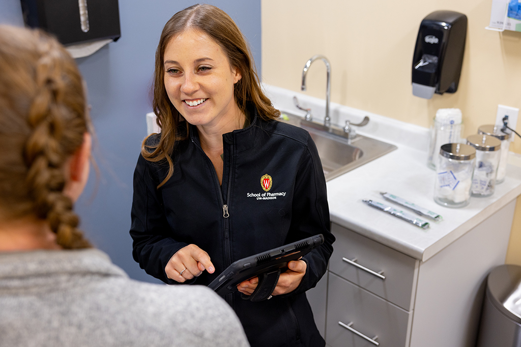 Emma Hickmann speaking with a woman while holding a tablet and smiling