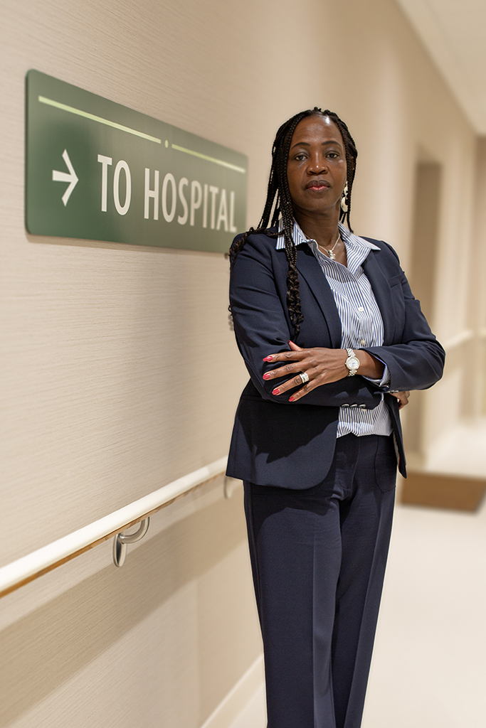 Hannet Tibagwa Ambord stands in a hallway near a "To Hospital" sign