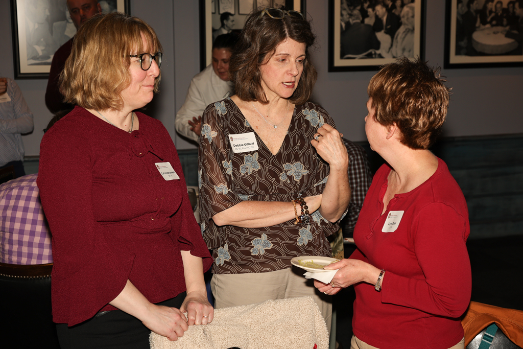 Carolyn Hermann, Debbie Gillard and another alum speak in a group