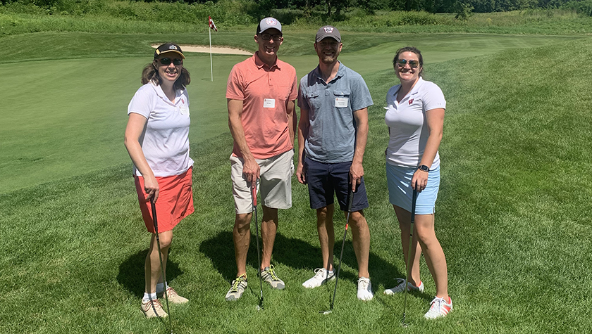 A group of alumni smile at the 2022 golf outing, outside in the sun